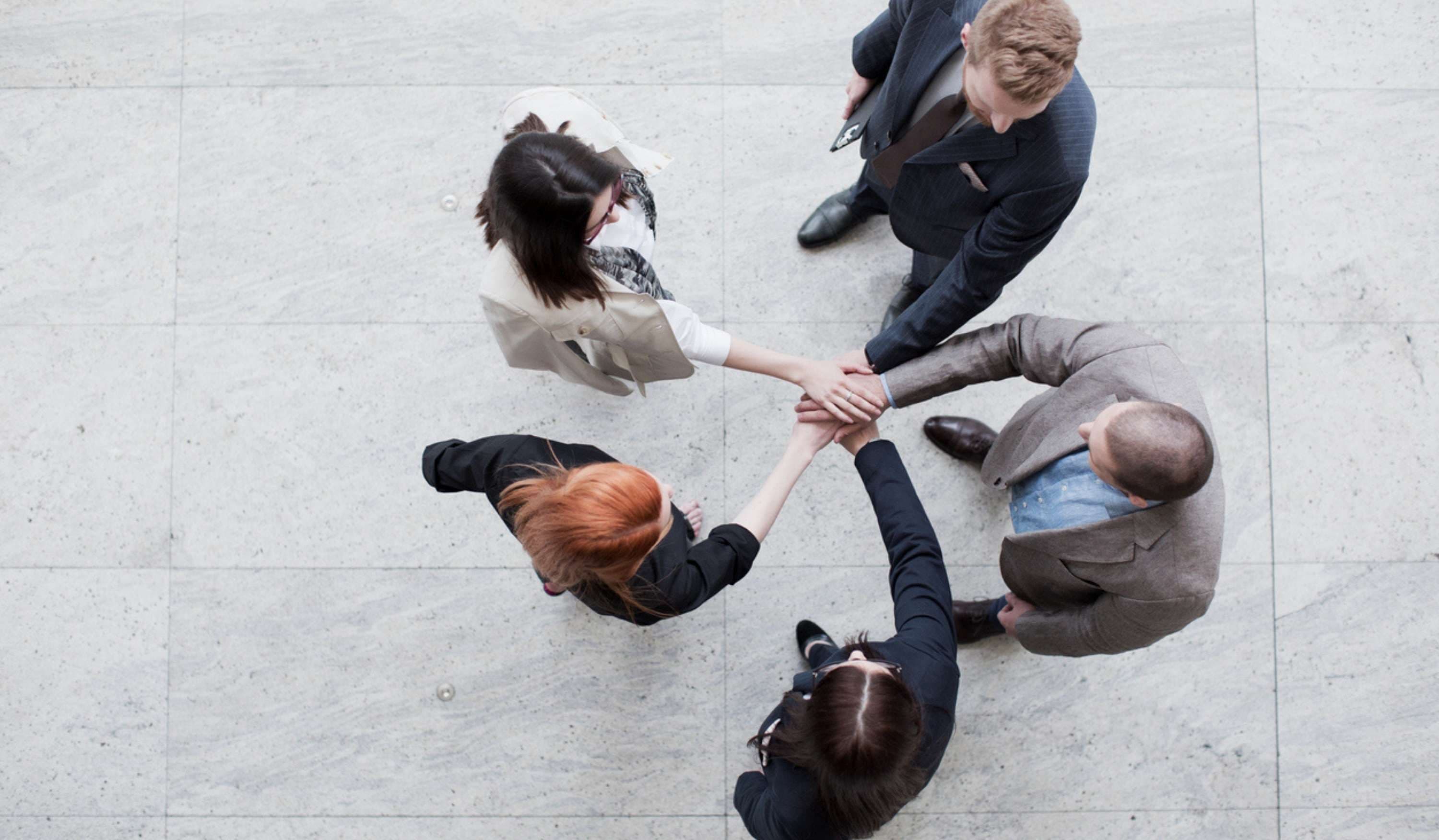 Geschäftsteam legt motiviert Hände übereinander