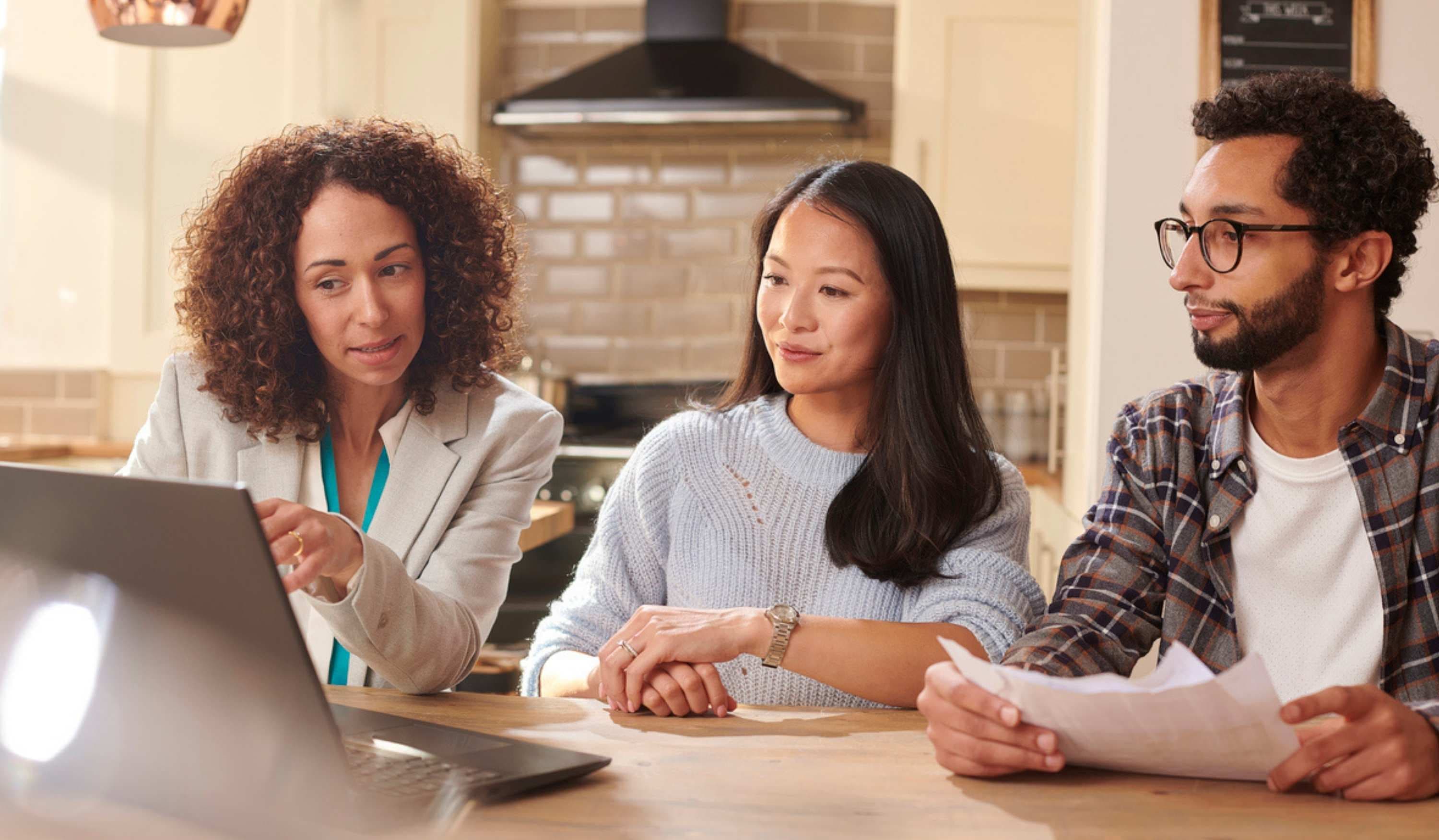 Beraterin erklärt einem jungen Paar Daten am Laptop